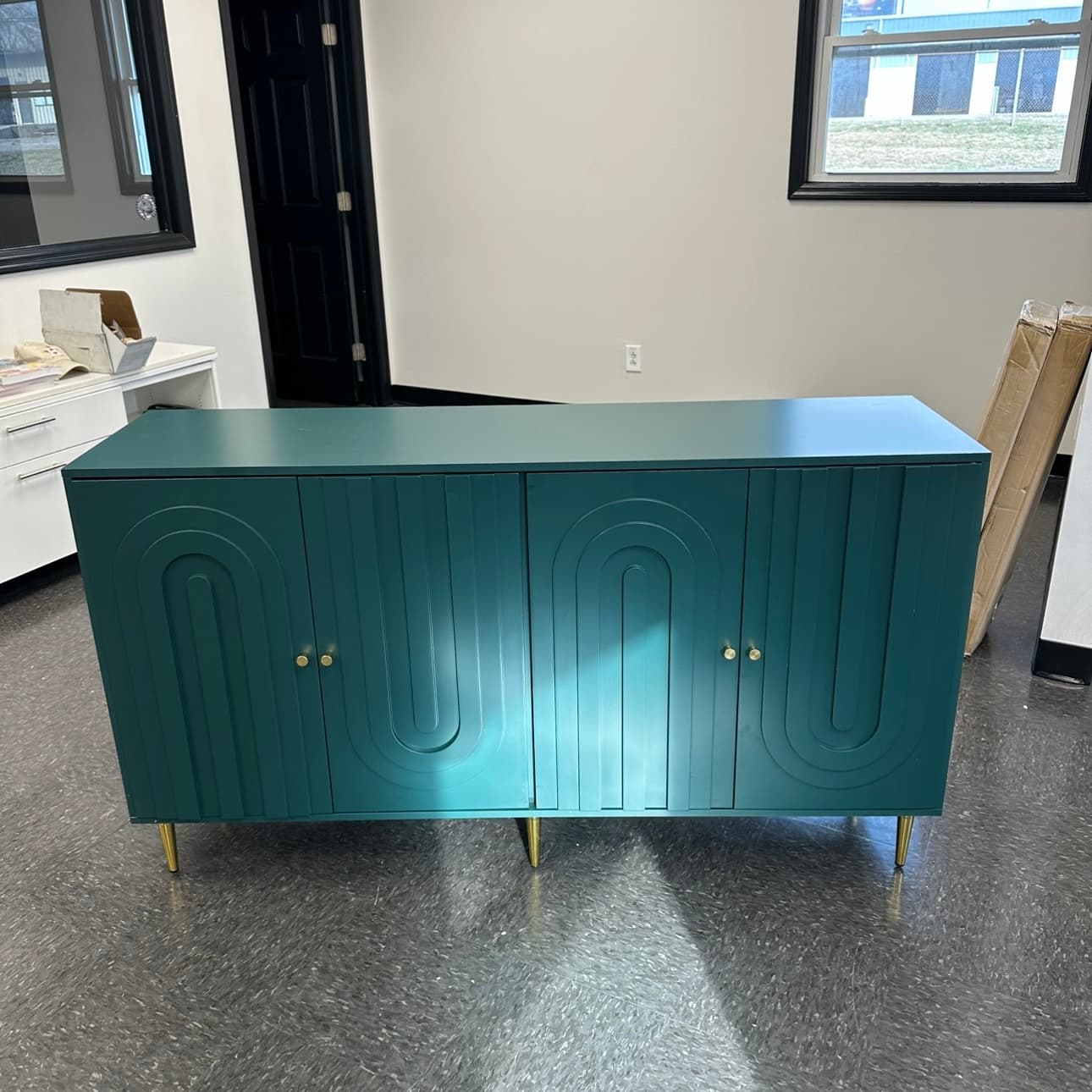 Deep green credenza with arched fluted doors and brass legs, assembled and standing level